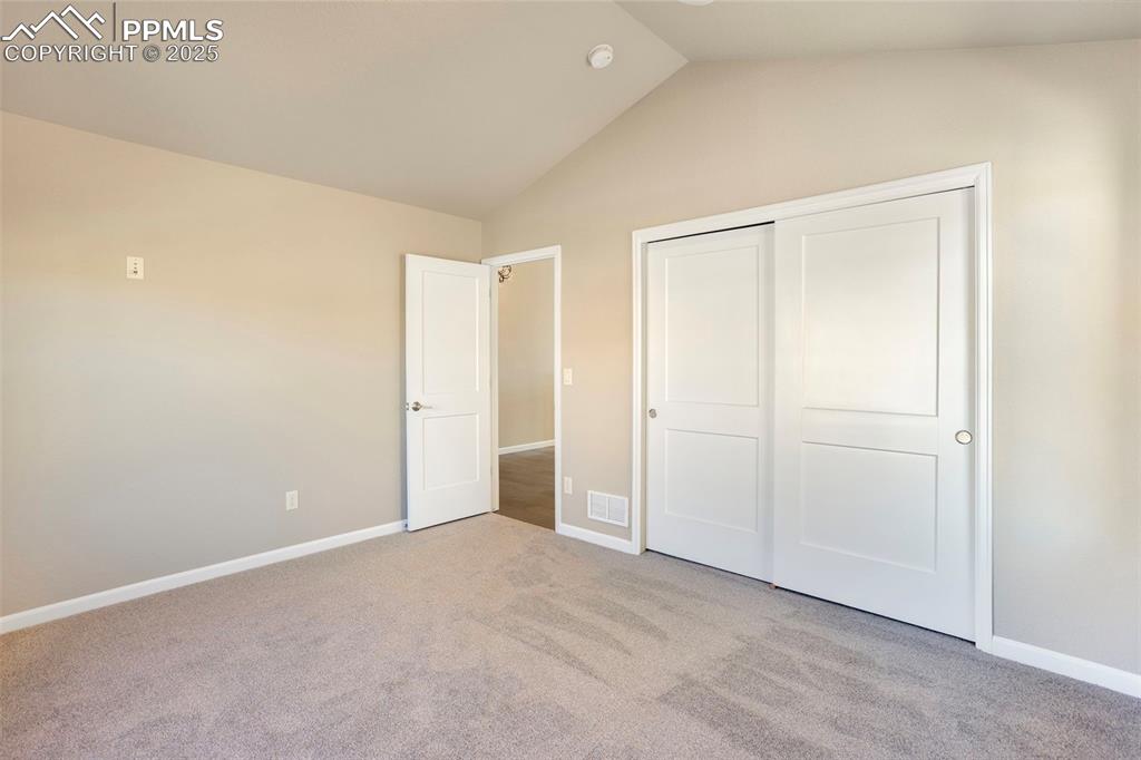 Image 23 of 48: Unfurnished bedroom with lofted ceiling, light colored carpet, and a closet