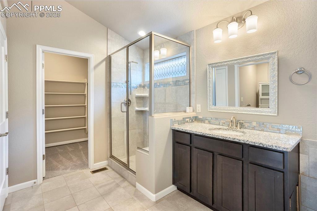 Image 25 of 48: Full bath featuring a spacious closet, vanity, light tile patterned floors,