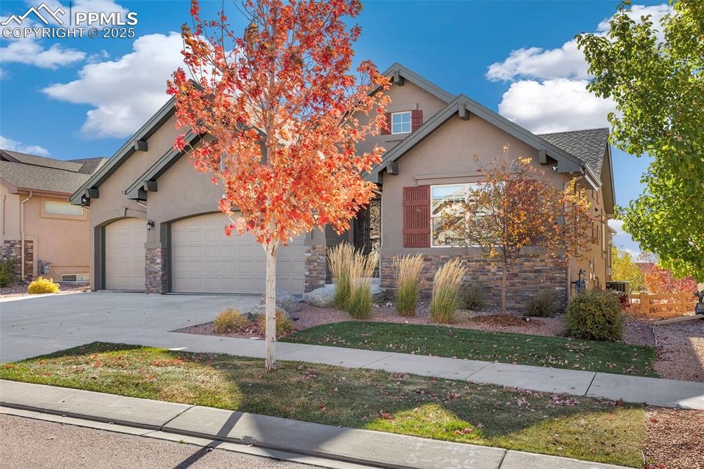 Image 3 of 48: View of front of home featuring concrete driveway, stucco siding, stone sid