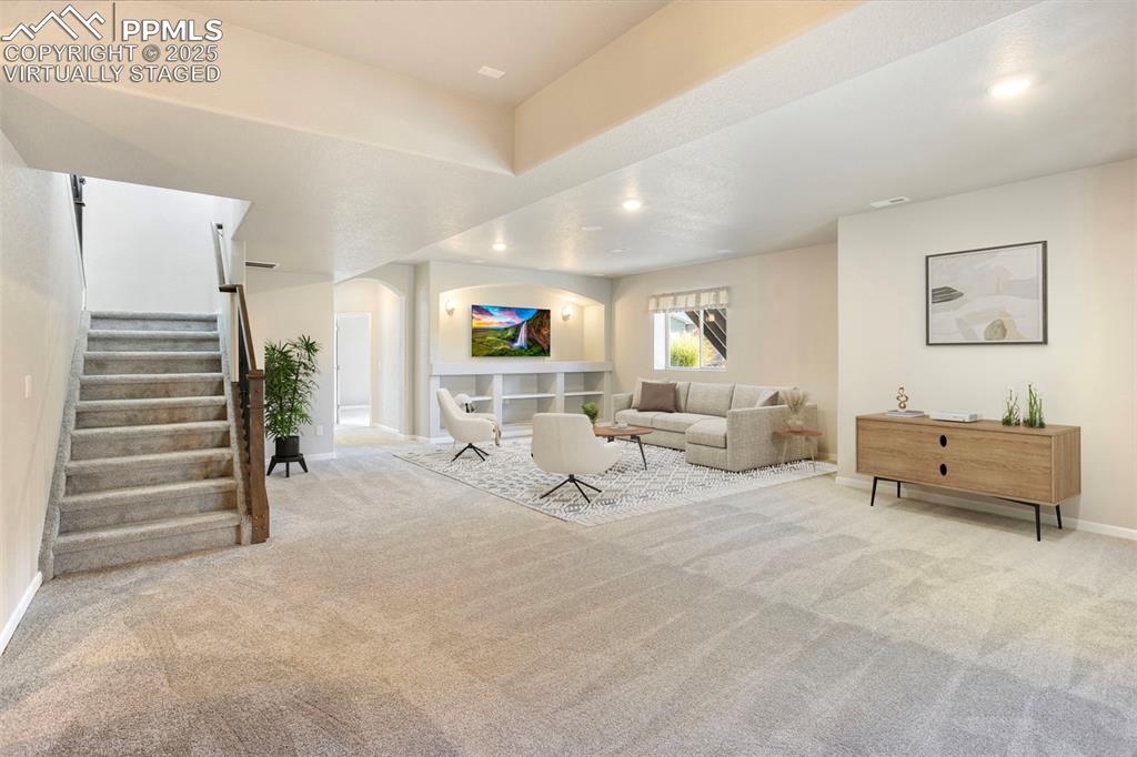 Image 30 of 48: Virtually Staged. Living area featuring light colored carpet, stairway, arc