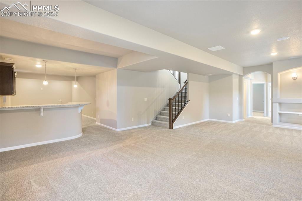 Image 32 of 48: Unfurnished living room with light carpet, recessed lighting, stairs, and a