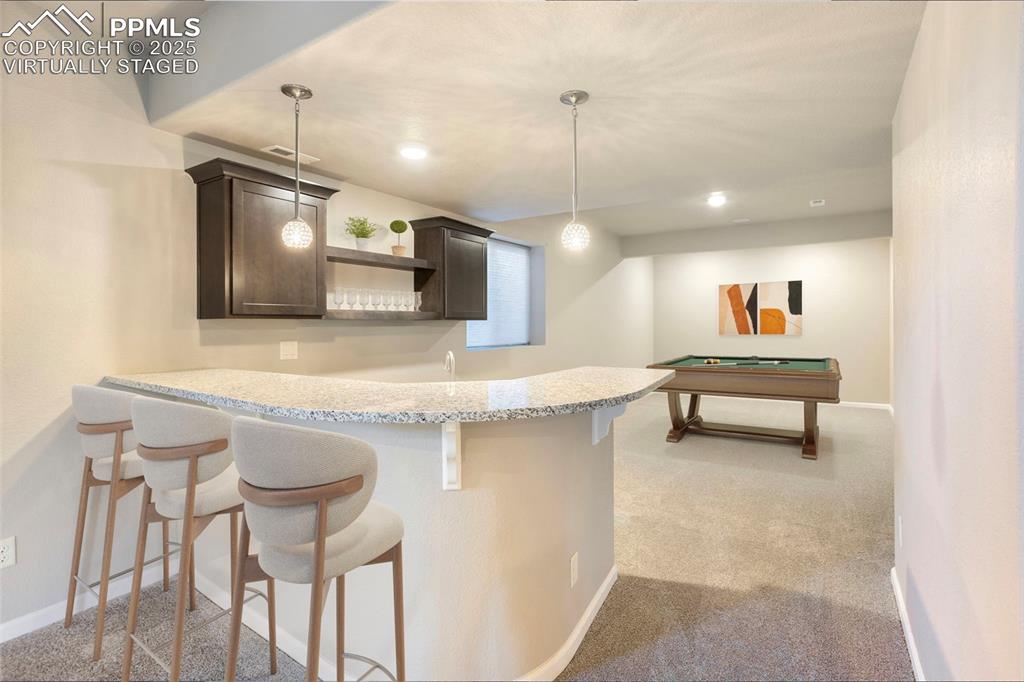 Image 35 of 48: Virtually Staged. Bar area with open shelves, dark brown cabinetry, light c