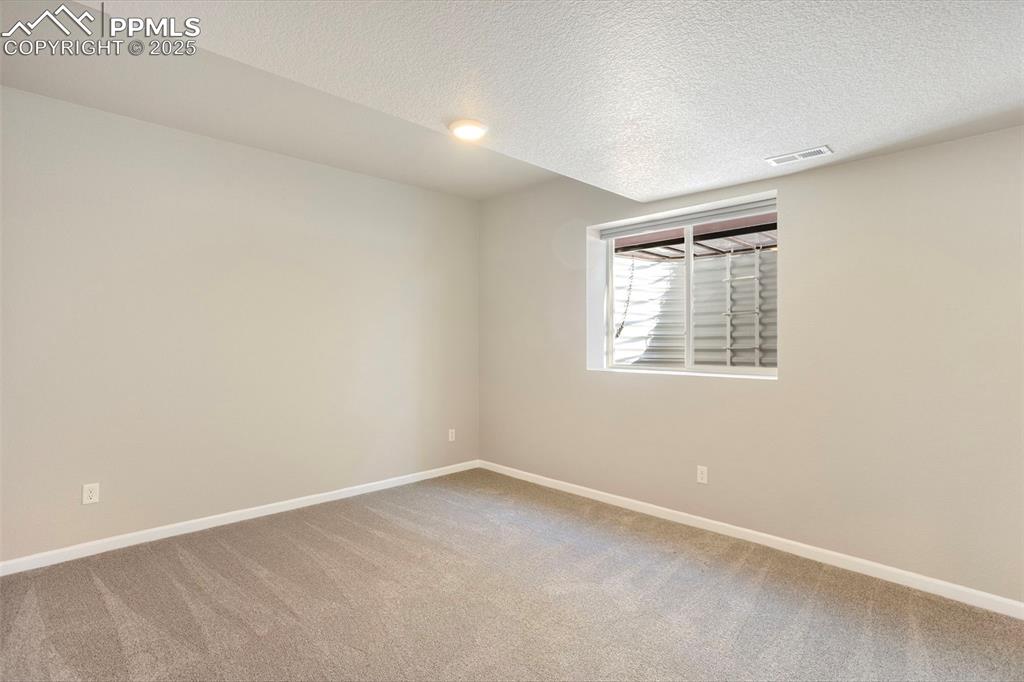 Image 39 of 48: Empty room featuring light colored carpet and a textured ceiling