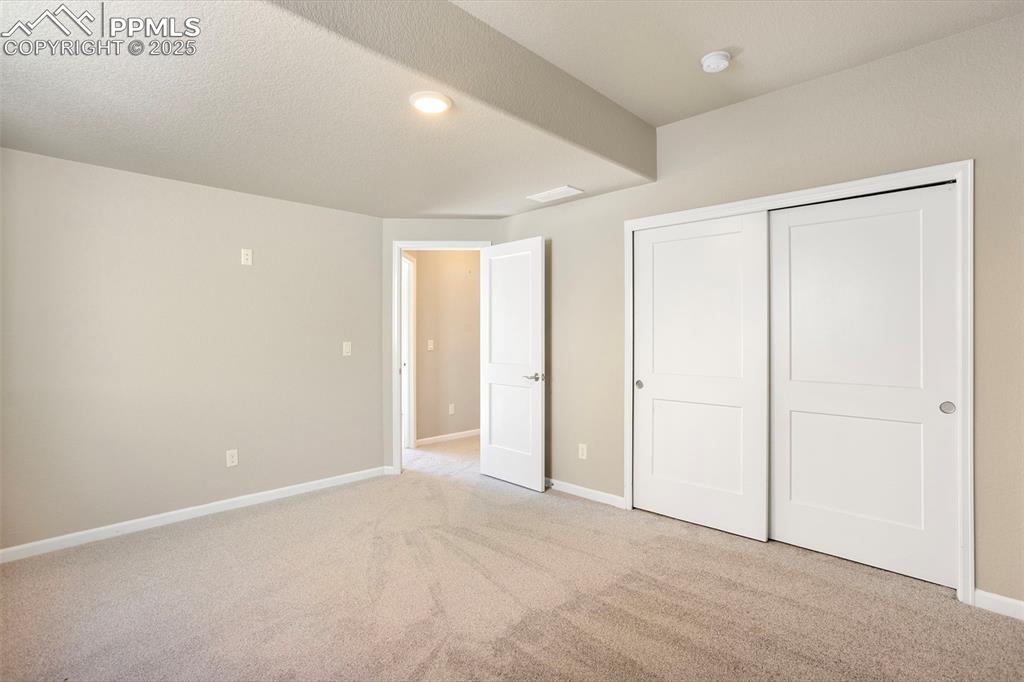 Image 40 of 48: Unfurnished bedroom with light colored carpet, a textured ceiling, and a cl