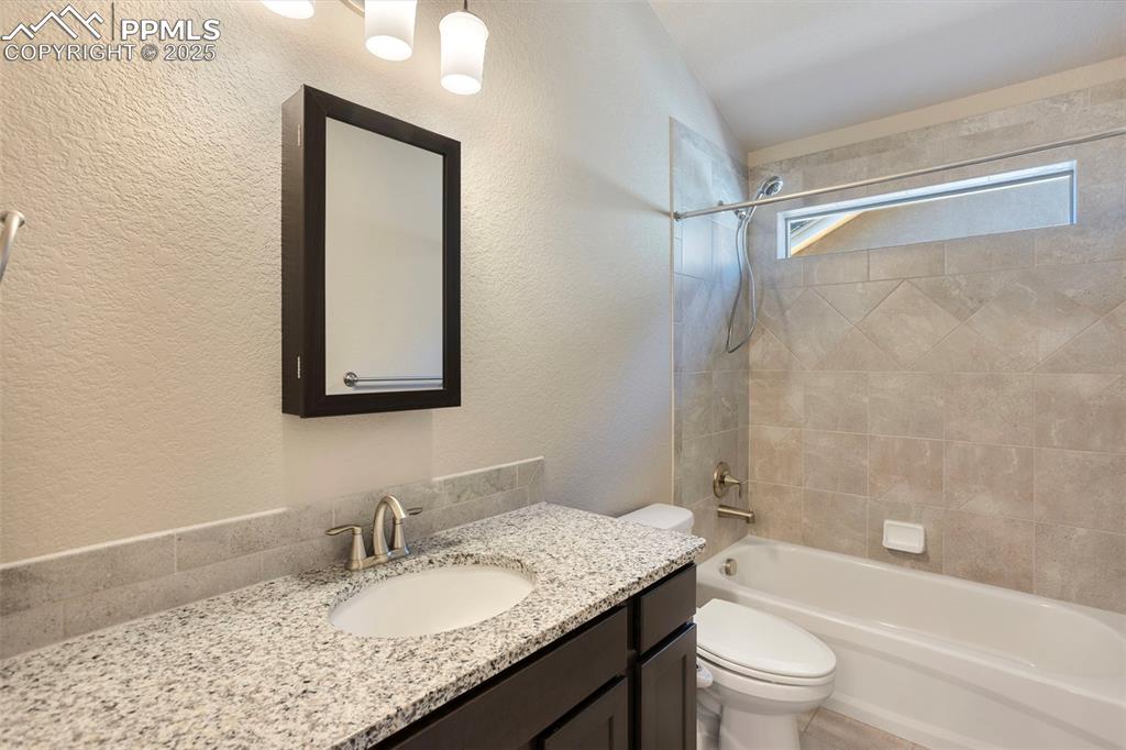 Image 41 of 48: Full bathroom featuring a textured wall, shower / tub combination, and vani