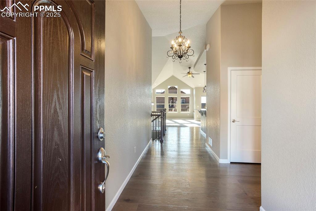 Image 6 of 48: Entrance foyer featuring dark wood-style floors, a textured wall, a chandel