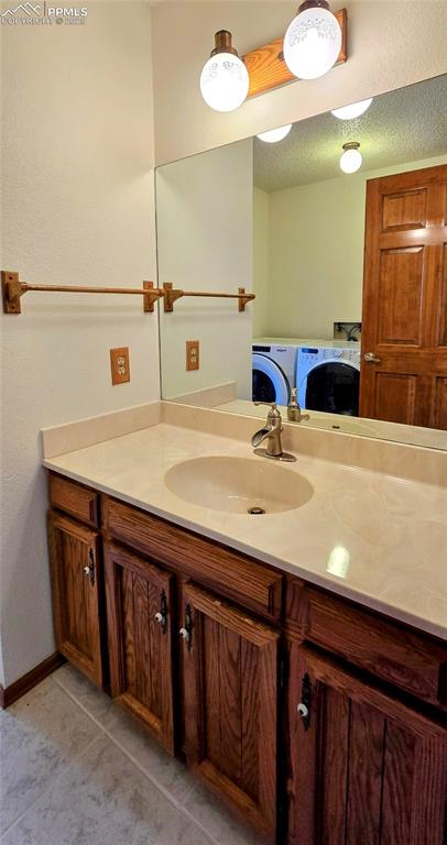 Image 14 of 22: Bathroom featuring vanity, independent washer and dryer, tile patterned flo