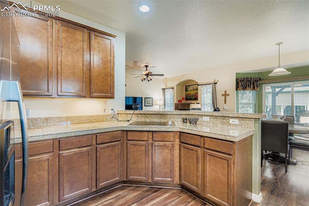 Image 13 of 29: Kitchen featuring brown cabinets, open floor plan,