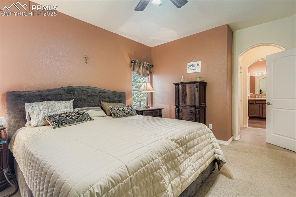 Image 17 of 29: Master Bedroom with a textured wall, light carpet, arched walkways, a ceili