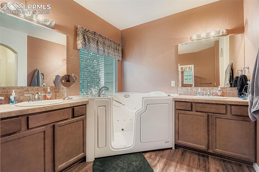 Image 18 of 29: Master Bathroom with a textured wall, two vanities, a step in whirlpool tub