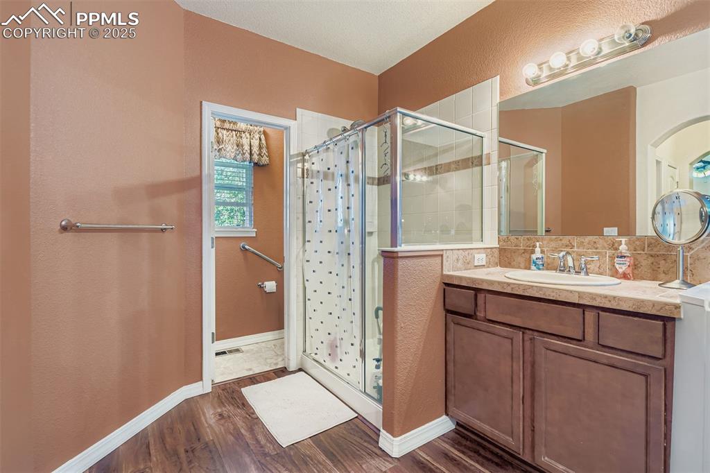 Image 19 of 29: Master Full bath with a stall shower, vanity, dark wood-type flooring