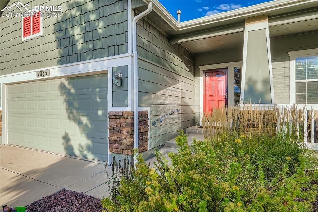 Image 5 of 29: View of exterior entry with a garage and stone siding