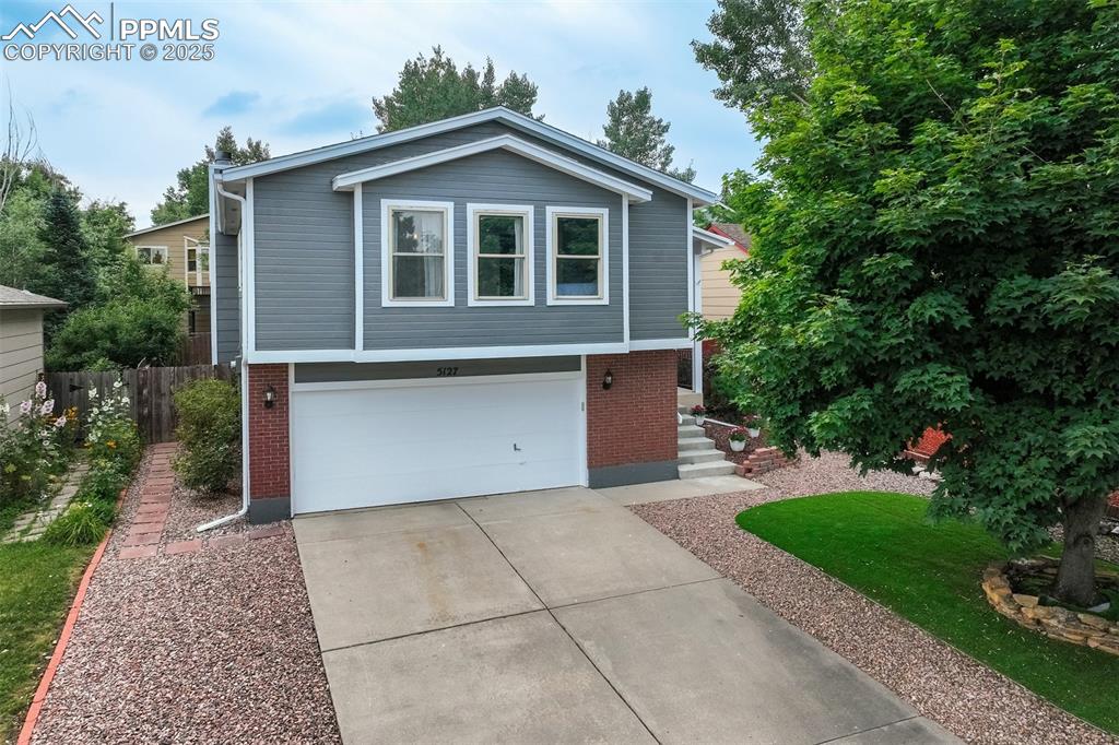 Caption: View of front facade featuring concrete driveway, brick siding, and an attached garage