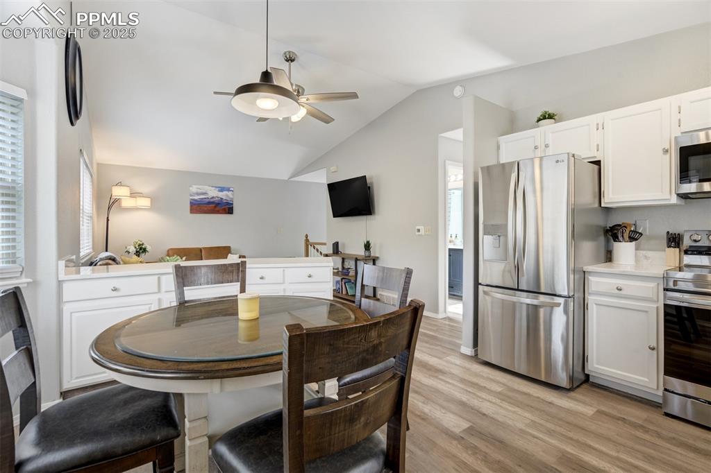 Image 11 of 36: Dining room featuring a ceiling fan, lofted ceiling, and light wood-style f