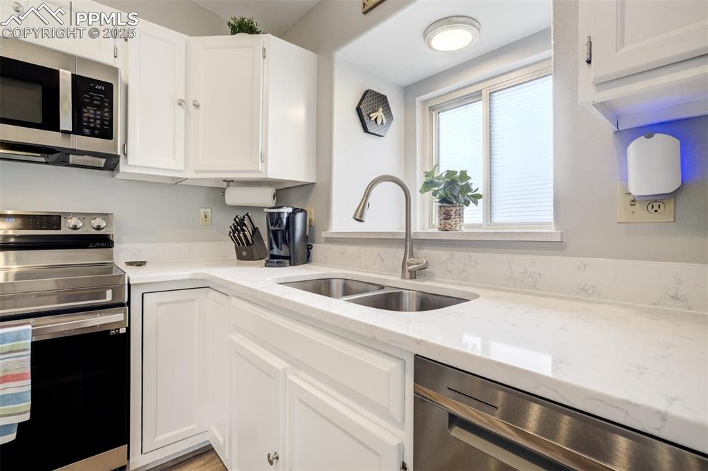 Image 13 of 36: Kitchen featuring stainless steel appliances, white cabinets, and light sto