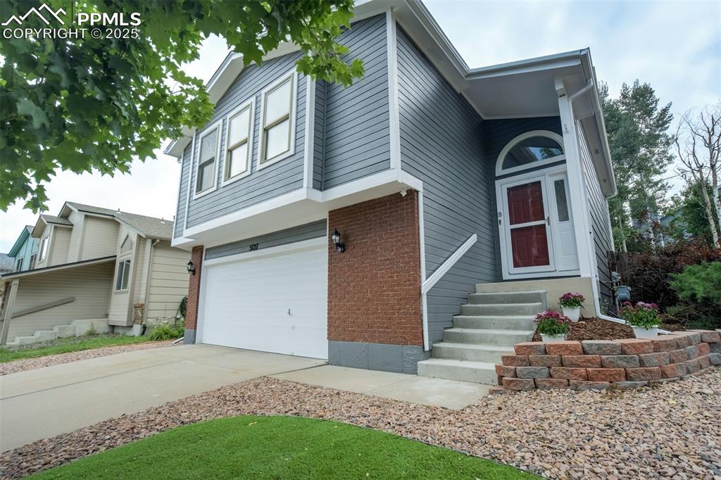 Image 2 of 36: View of front of house featuring a garage, driveway, brick siding, and entr