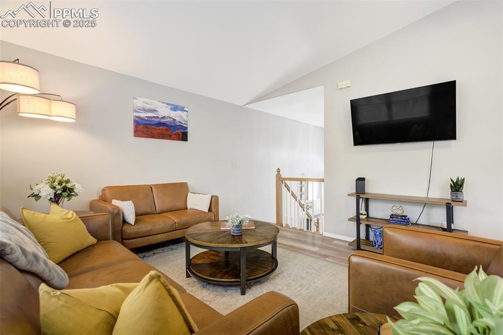 Image 8 of 36: Living area with wood finished floors and lofted ceiling