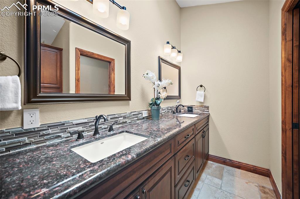 Image 20 of 47: Bathroom featuring double vanity, stone tile flooring, and a textured wall
