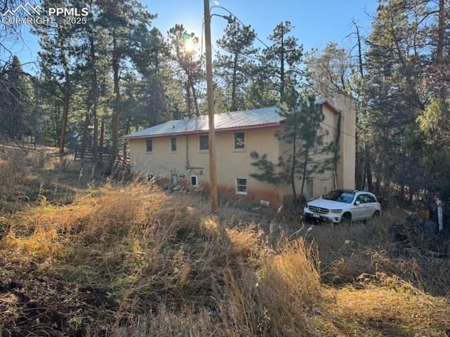 Image 2 of 3: View of side of property featuring a chimney and a metal roof