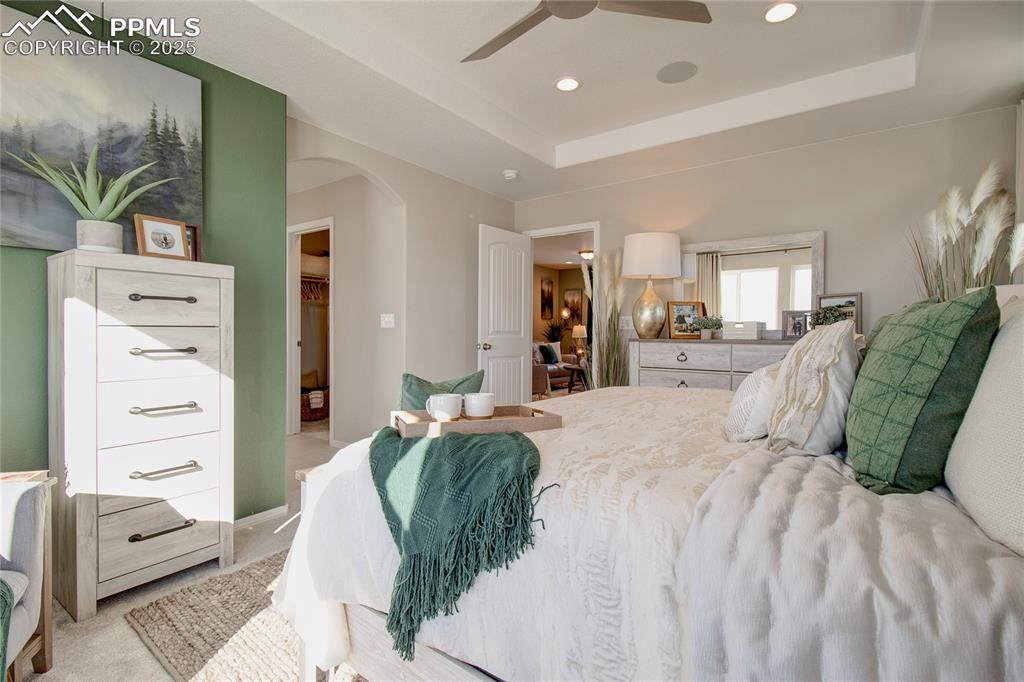 Image 12 of 32: Bedroom featuring arched walkways, light carpet, recessed lighting, a raise