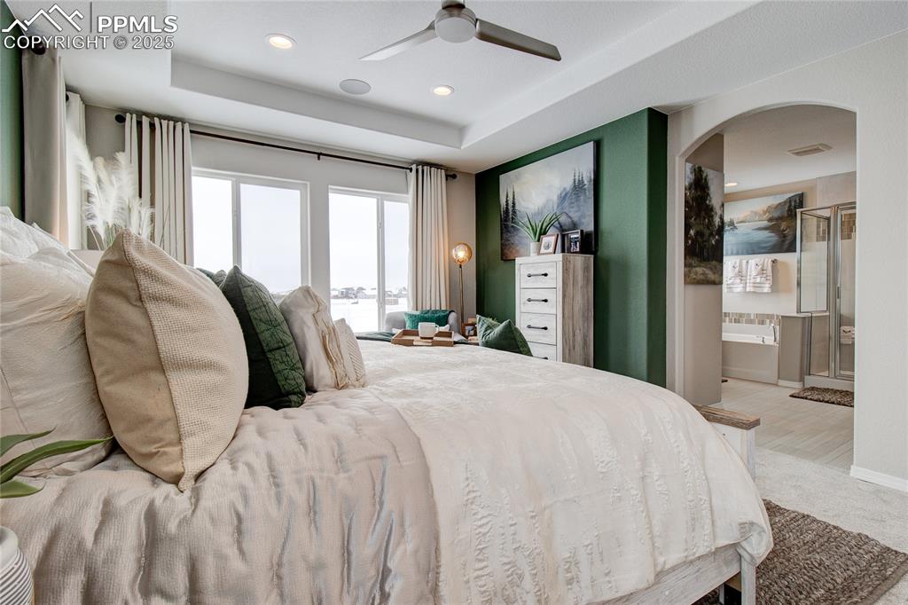 Image 24 of 32: Bedroom with arched walkways, a raised ceiling, recessed lighting, ensuite 