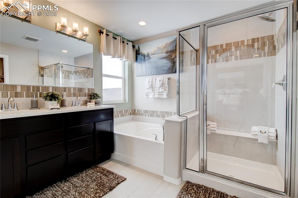 Image 25 of 32: Bathroom with a stall shower, a garden tub, double vanity, backsplash, and 