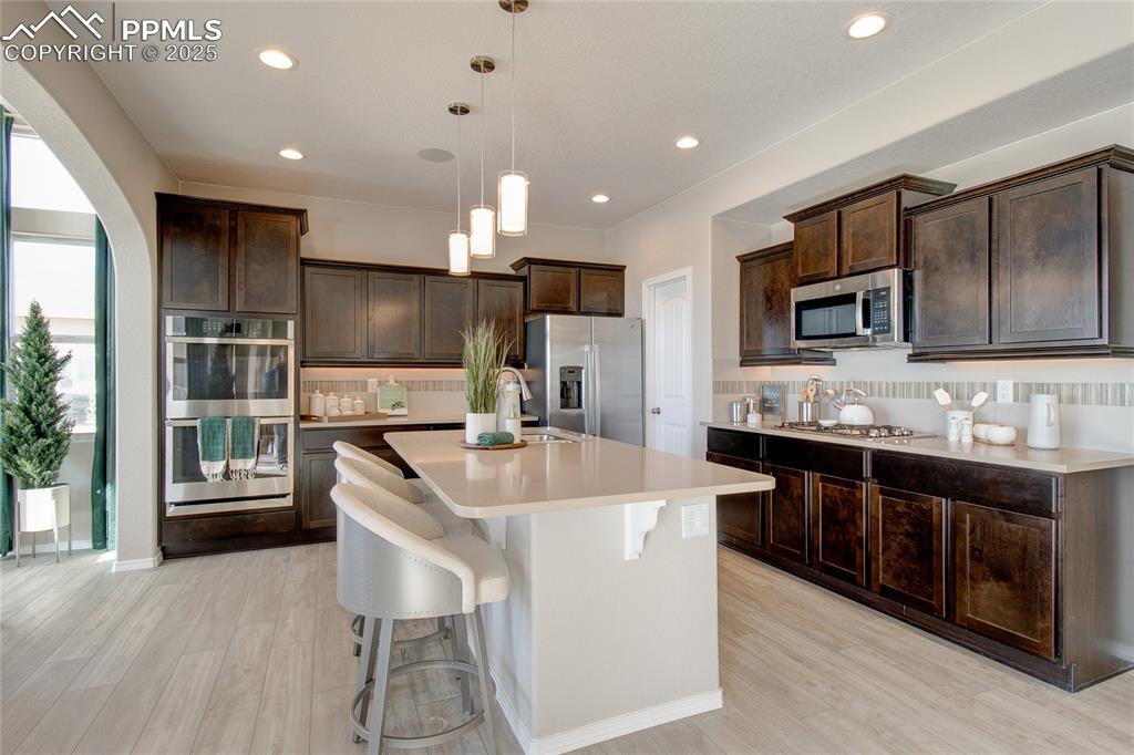 Image 4 of 32: Kitchen featuring appliances with stainless steel finishes, decorative back