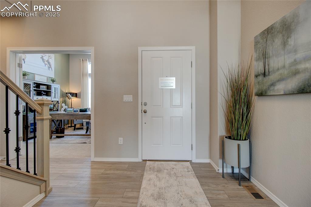 Image 8 of 32: Foyer entrance with light wood-style floors and stairs