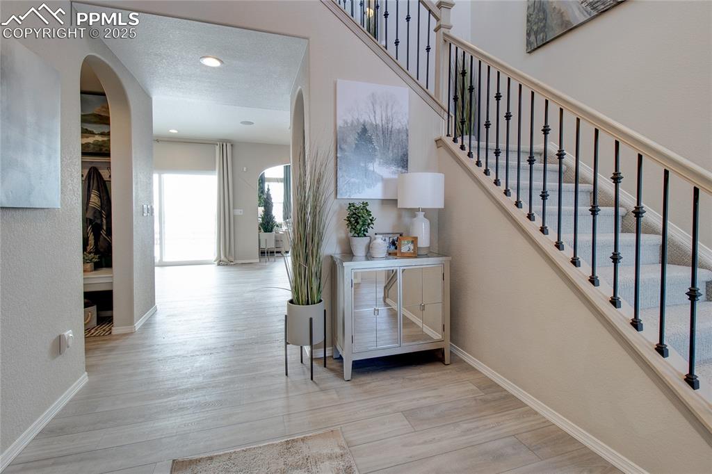 Image 9 of 32: Stairway featuring arched walkways, wood finished floors, and recessed ligh