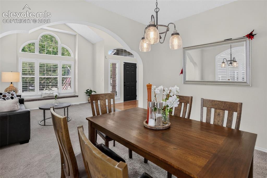 Image 13 of 49: Dining area featuring a dark wood-finish table and chairs, illuminated by a