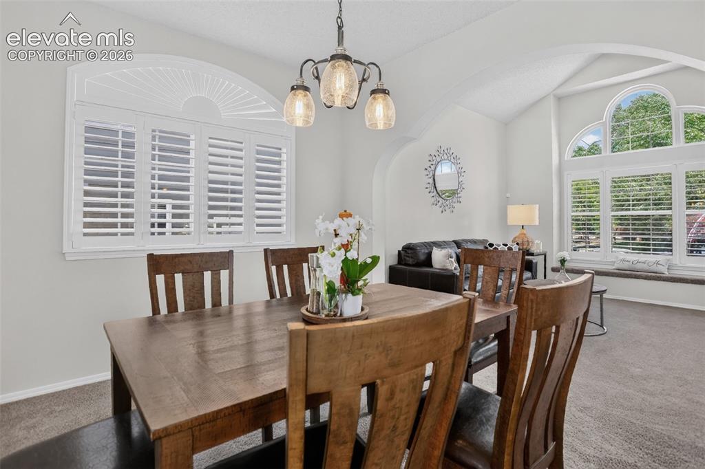 Image 14 of 49: Dining area featuring a contemporary chandelier, arched entryway, and a lar
