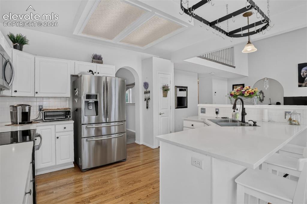 Image 15 of 49: Kitchen featuring white cabinetry, stainless steel appliances, a large isla