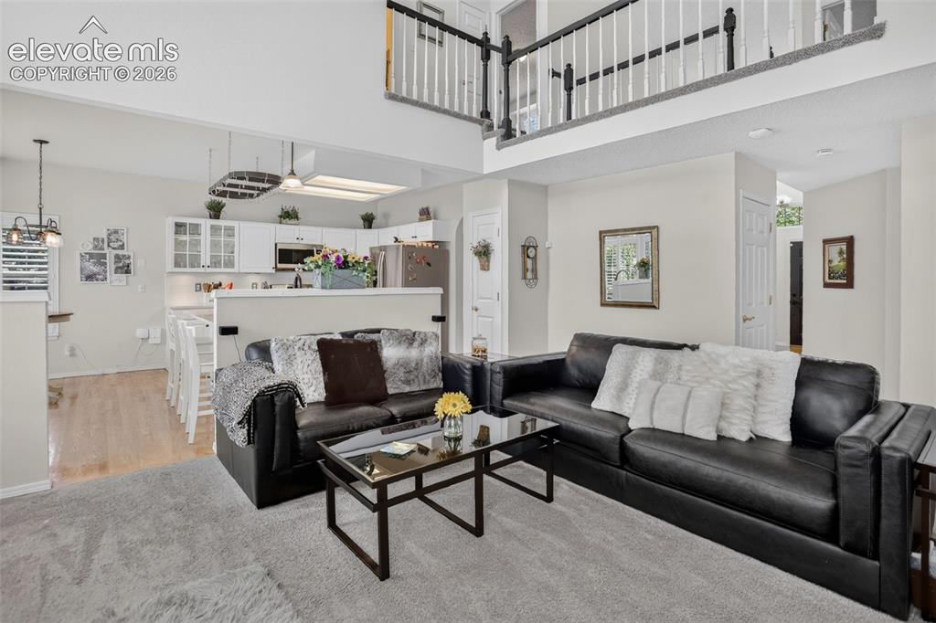 Image 19 of 49: Spacious living area featuring high ceilings and a second-story balcony