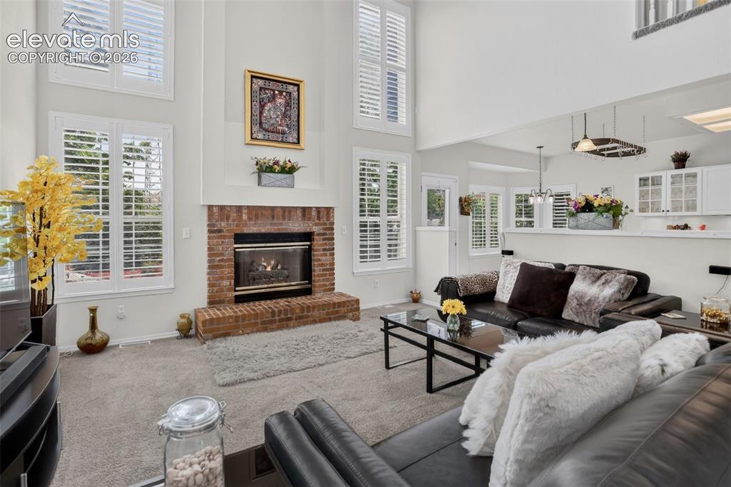 Image 20 of 49: Living room featuring a brick fireplace with a gas insert, high ceilings, m