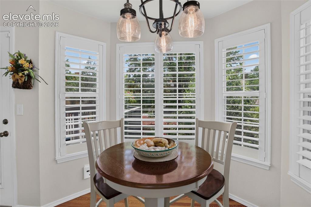 Image 22 of 49: Bay window dining area with white plantation shutters and wood-finish floor