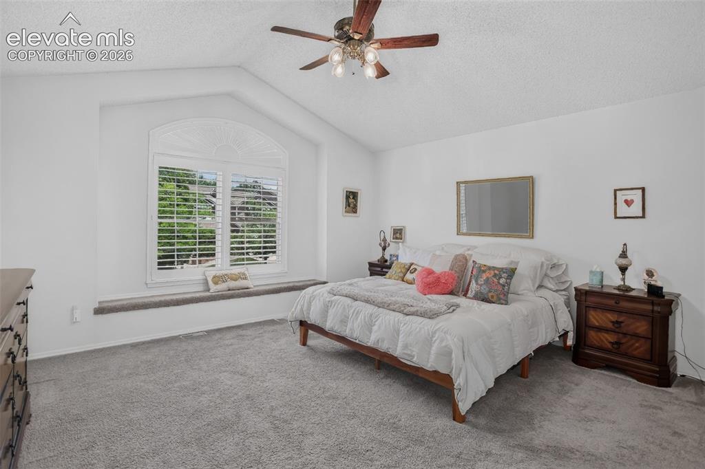 Image 24 of 49: Vaulted ceiling with a ceiling fan, arched window with plantation shutters,