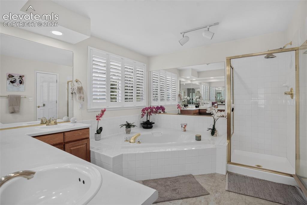 Image 27 of 49: Spa-inspired bath featuring a jetted soaking tub with tile surround, separa