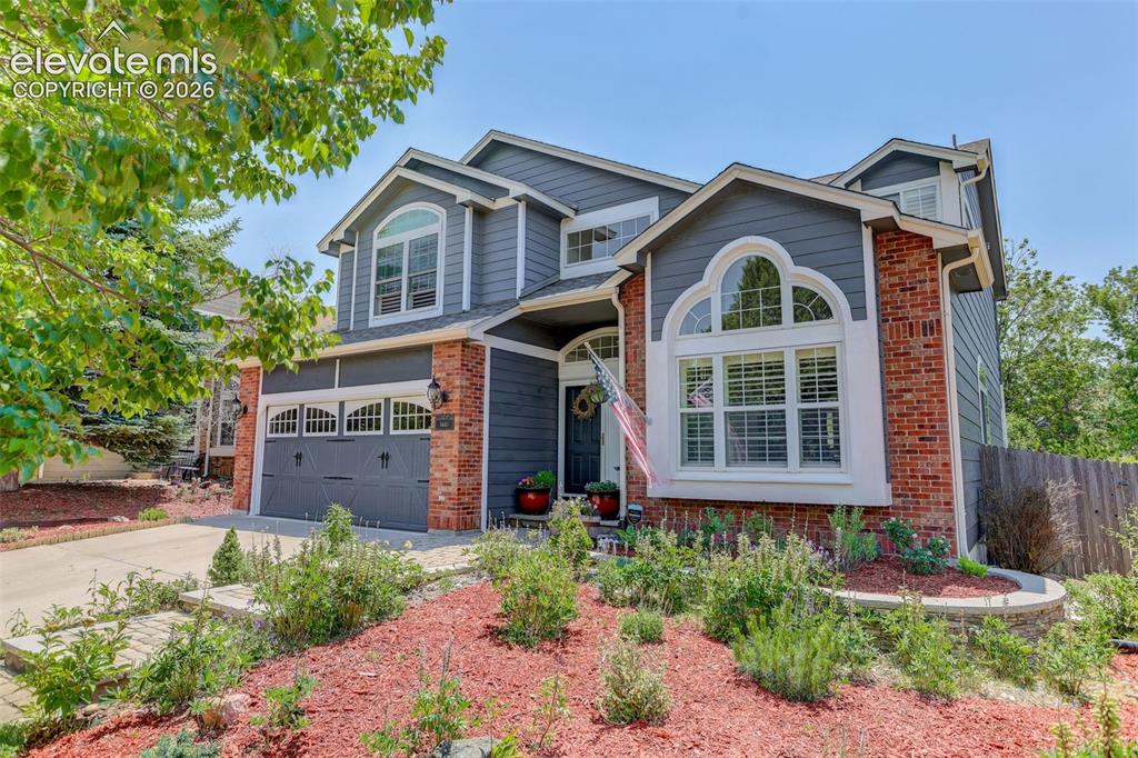 Image 4 of 49: Two-story residence featuring brick and siding exterior, arched window acce