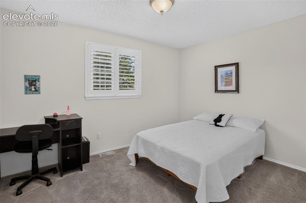 Image 43 of 49: Bright room featuring neutral wall tones, textured ceiling, window with pla