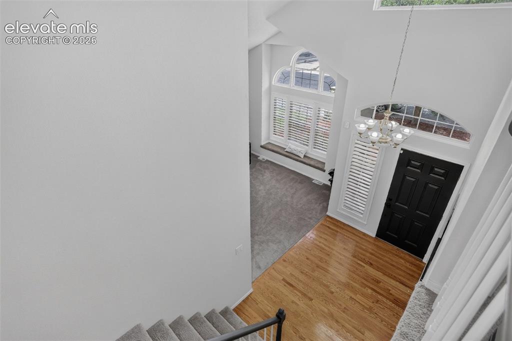 Image 8 of 49: Two-story foyer featuring hardwood flooring, a black paneled front door, an