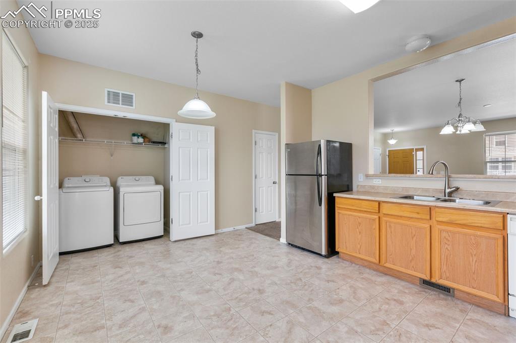 Image 17 of 38: Kitchen featuring freestanding refrigerator, a chandelier, separate washer 