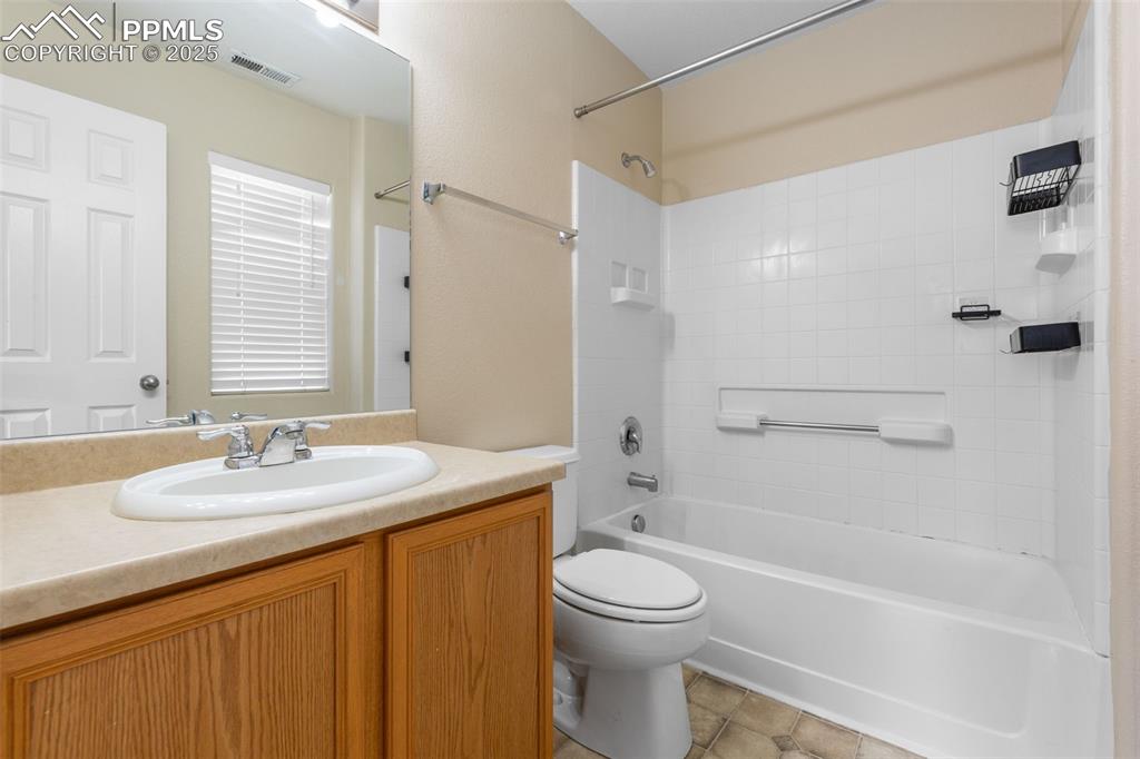 Image 25 of 38: Primary Ensuite Bathroom featuring vanity,  shower combination, and tile pa