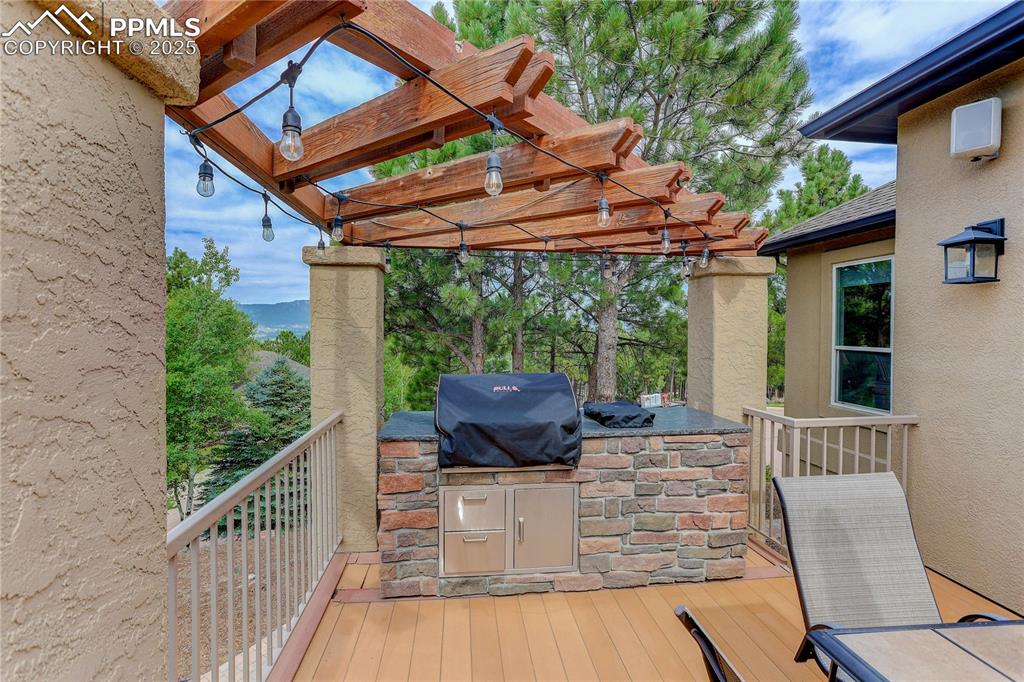 Image 35 of 45: Built-in stone BBQ grill with side burner and patio lighting on PERGOLA