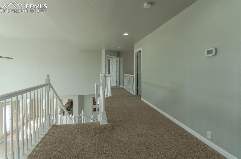 Image 23 of 45: Hallway with an upstairs landing, carpet flooring, and recessed lighting