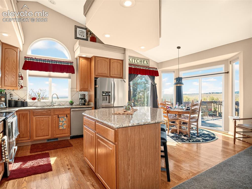Image 10 of 49: Kitchen with hardwood floors, granite counters and island looking towards d