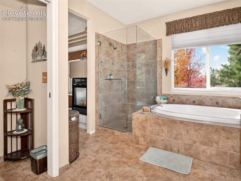 Image 23 of 49: Primary bathroom shower and large soaking tub with views of Pikes Peak.