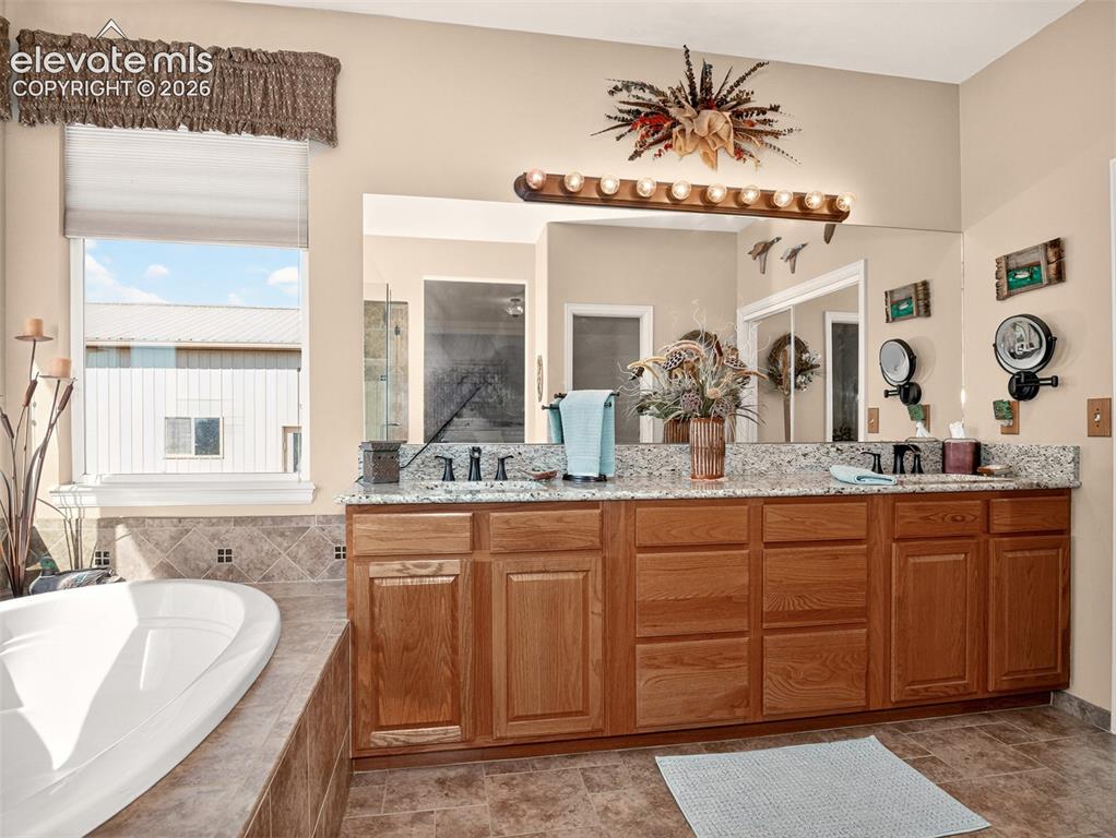 Image 24 of 49: Primary bathroom with dual sinks and large soaking tub.
