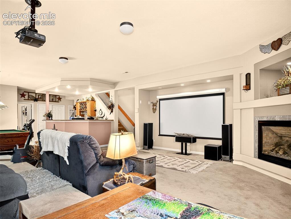 Image 29 of 49: Living area in basement set up as a theatre room with gas fireplace.