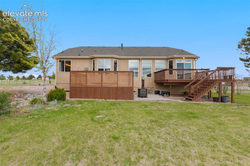 Image 38 of 49: Back view of the home showing the deck and privacy fence around the hot tub