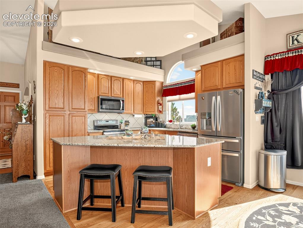 Image 9 of 49: Kitchen island with granite counter tops and stainless steel appliances.